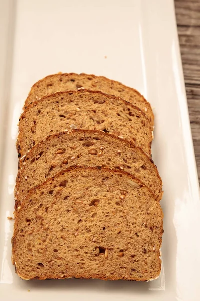 Bruin meergranen brood segmenten op een witte plaat — Stockfoto