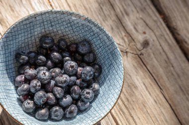 Mavi ve beyaz bir kase içinde organik yaban mersini