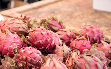 Bir çiftçi pazarda satılan bir sepet içinde kırmızı dragon meyve