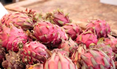 Bir çiftçi pazarda satılan bir sepet içinde kırmızı dragon meyve