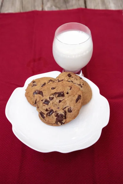 Schokoladenkekse auf einem weißen Teller mit Vollmilch — Stockfoto
