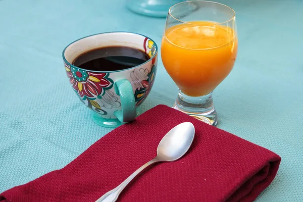 Svart kaffe i en färgsprakande blomma print kopp med apelsinjuice — Stockfoto