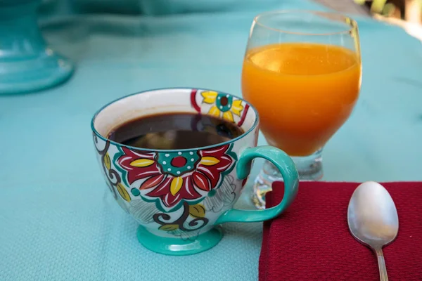 Café negro en una taza de impresión de flores de colores con jugo de naranja —  Fotos de Stock