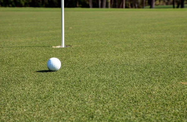 Golf topu ve yemyeşil yeşil çimenlerin üzerinde bayrak — Stok fotoğraf