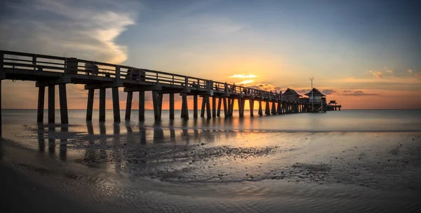 Cais de Nápoles na praia ao pôr do sol — Fotografia de Stock