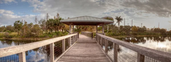 Sonnenuntergang über Pavillon auf einer ruhigen Holzpromenade — Stockfoto