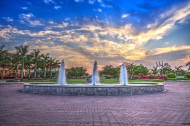 Napoli, Florida 'da yansıtıcı bir havuzda üç spreyli bir çeşmenin üzerinde gün batımı