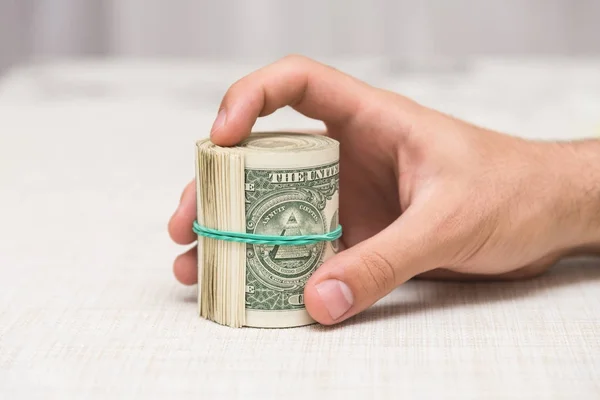 Bir adam elinde bir elastik bant ile bağlı bir tomar para tutar