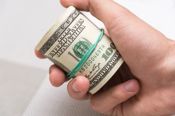 Muž drží svazek peníze v ruce svázané s gumičkou — Stock fotografie