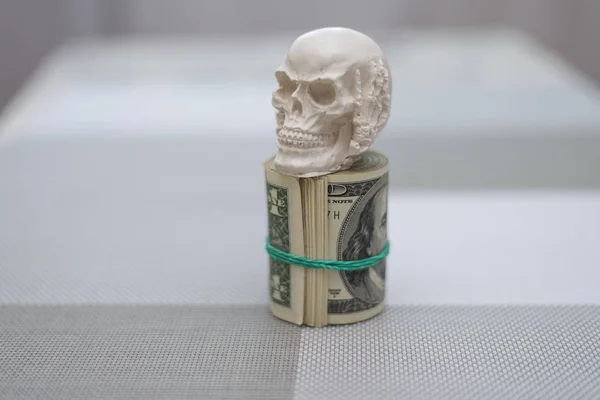 A skull standing on a bundle of money, twisted into a bundle — Stock Photo, Image