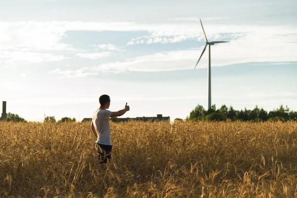 Bir rüzgar jeneratör bakarak bir alanda bir adam