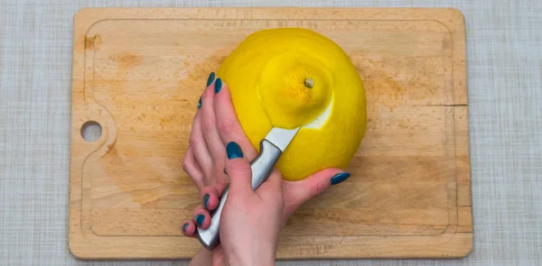 Girl cleans a pomelo on a wooden board — Stock Photo, Image