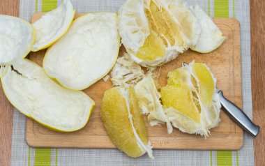 Kız bir pomelo ahşap tahta üzerinde temizler