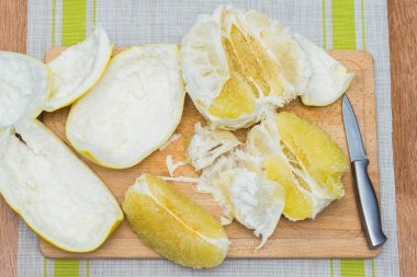 Kız bir pomelo ahşap tahta üzerinde temizler
