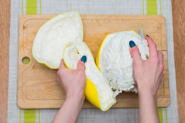 Kız bir pomelo ahşap tahta üzerinde temizler