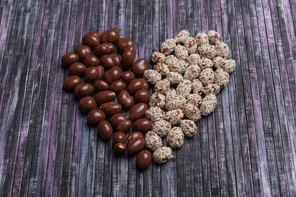 Peanuts in chocolate. Peanut with caramel and sesame seeds. Sweet peanut posted heart.