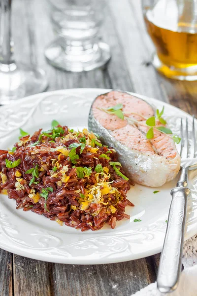 Bife de salmão com arroz vermelho. Arroz vermelho com raspas de salmão e limão — Fotografia de Stock