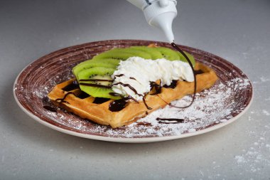 Kivi, krema ve çikolata ile Belçika waffle tabak