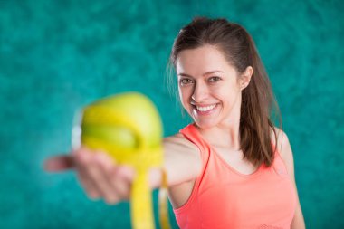 Diyet. Elma ve tape ölçmek için diyet ve kilo kaybı kavramı - turkuaz arka plan üzerinde izole sağlıklı mutlu kadın var. Tatlılar sağlıksız. Abur cubur. 