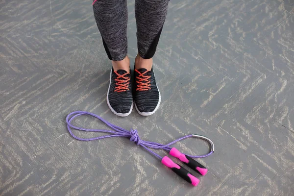 Sport shoes and jumping rope on wooden background