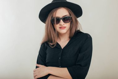 Güzel moda olan kadın siyah şapka ve gözlük gri arka plan üzerinde moda makyaj. Modeli şık gözlük takıyor kameraya bakıyor. Kadın moda, güzellik kavramı. 