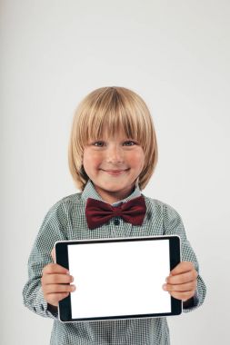 Tablet bilgisayar beyaz arka planda tutan gülümseyen okullu çocuk gömlek ile kırmızı papyon,