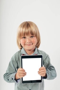 Tablet bilgisayar beyaz arka planda tutan gülümseyen okullu çocuk gömlek ile kırmızı papyon,