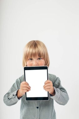 Tablet bilgisayar beyaz arka planda tutan gülümseyen okullu çocuk gömlek ile kırmızı papyon,