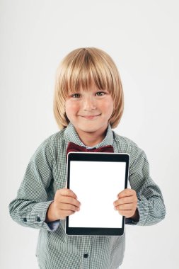 Tablet bilgisayar beyaz arka planda tutan gülümseyen okullu çocuk gömlek ile kırmızı papyon,