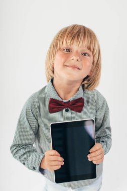 Tablet bilgisayar beyaz arka planda tutan gülümseyen okullu çocuk gömlek ile kırmızı papyon,