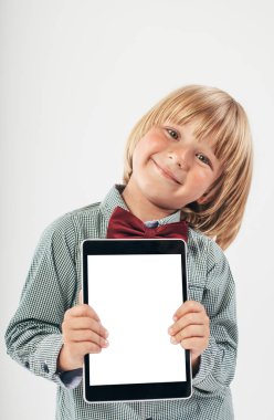 Tablet bilgisayar beyaz arka planda tutan gülümseyen okullu çocuk gömlek ile kırmızı papyon,