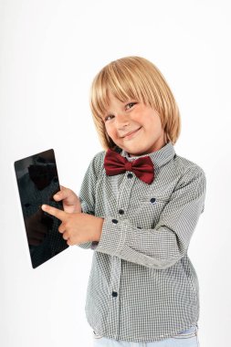 Tablet bilgisayar beyaz arka planda tutan gülümseyen okullu çocuk gömlek ile kırmızı papyon,