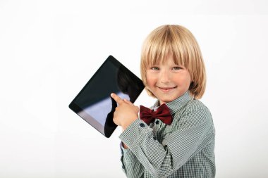 Tablet bilgisayar beyaz arka planda tutan gülümseyen okullu çocuk gömlek ile kırmızı papyon,