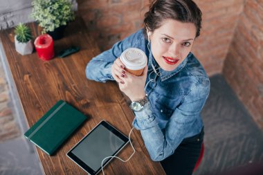Not defteri ve tablet ile güzel genç kadın serbest meslek çatı iç odasında bir kahve molası var