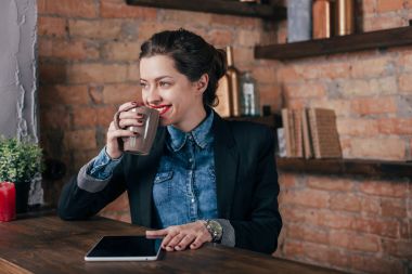 Not defteri ve tablet ile güzel genç kadın serbest meslek çatı iç odasında bir kahve molası var