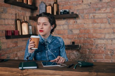 Not defteri ve tablet ile güzel genç kadın serbest meslek çatı iç odasında bir kahve molası var