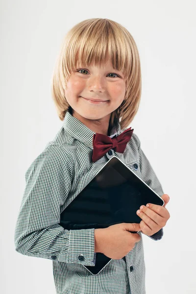 赤い蝶ネクタイ付きシャツ ホワイト バック グラウンドでタブレット コンピューターを保持している児童の笑顔 — ストック写真