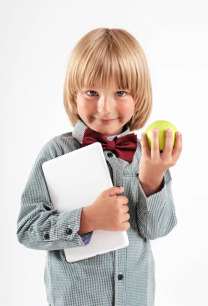 赤い蝶ネクタイ付きシャツ ホワイト バック グラウンドでタブレット コンピューターと青リンゴを保持している児童の笑顔 — ストック写真
