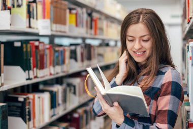 Kütüphane kitap ile gülümseyen genç kız öğrenci