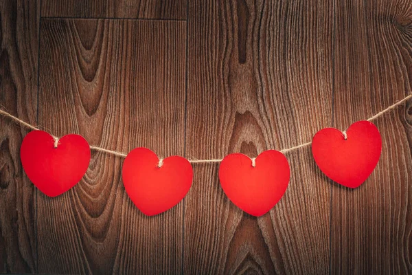 Love Valentine\'s hearts and card natural cord and red clips hanging on rustic driftwood texture background, copy space