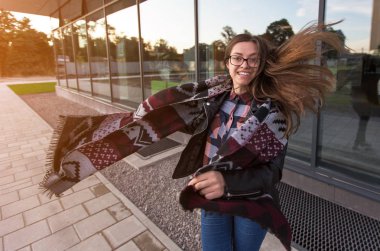 Sonbahar günbatımı modern mimarinin yakınındaki genç gülümseyen kız öğrenci