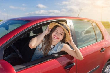 Genç kadın arabada. Bir araba bir kız. Gülümseyen genç kadın kırmızı arabada oturan