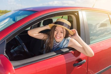 Genç kadın arabada. Bir araba bir kız. Gülümseyen genç kadın kırmızı arabada oturan
