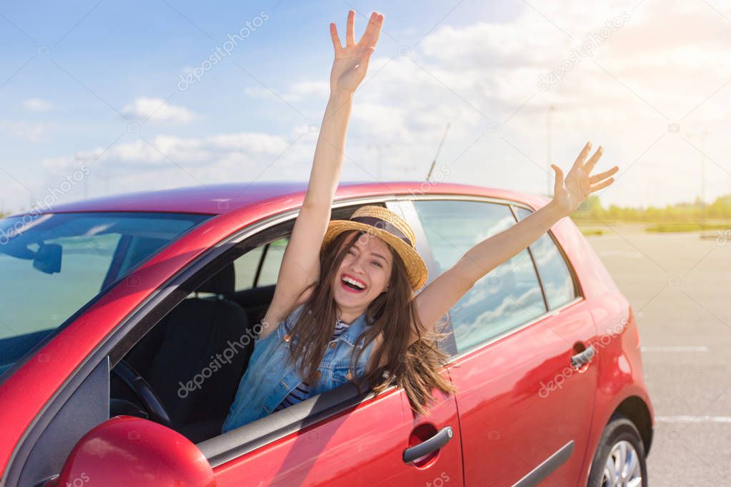Young woman in car. Girl driving a car.  Smiling young woman sitting in red car