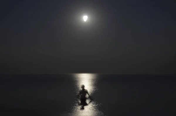 Silhouette of man in sea at night