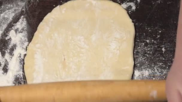 Женские руки выкатывают тесто на стол — стоковое видео