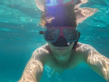 Sualtı maskesi olan bir adam denizde yüzüyor