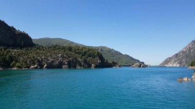 Oimapinar Barajı 'nın çevresindeki dağ kayalıkları arasında bir gölde seyreden bir tekne görüntüsü. Yeşil Kanyon, Manavgat, Antalya, Türkiye