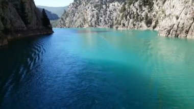 Oimapinar Barajı 'nın çevresindeki dağ kayalıkları arasında bir gölde seyreden bir tekne görüntüsü. Yeşil Kanyon, Manavgat, Antalya, Türkiye