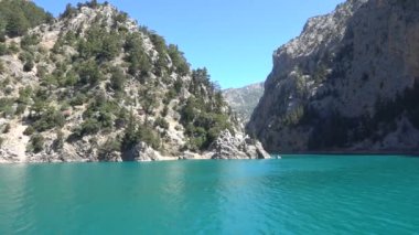 Oimapinar Barajı 'nın çevresindeki dağ kayalıkları arasında bir gölde seyreden bir tekne görüntüsü. Yeşil Kanyon, Manavgat, Antalya, Türkiye
